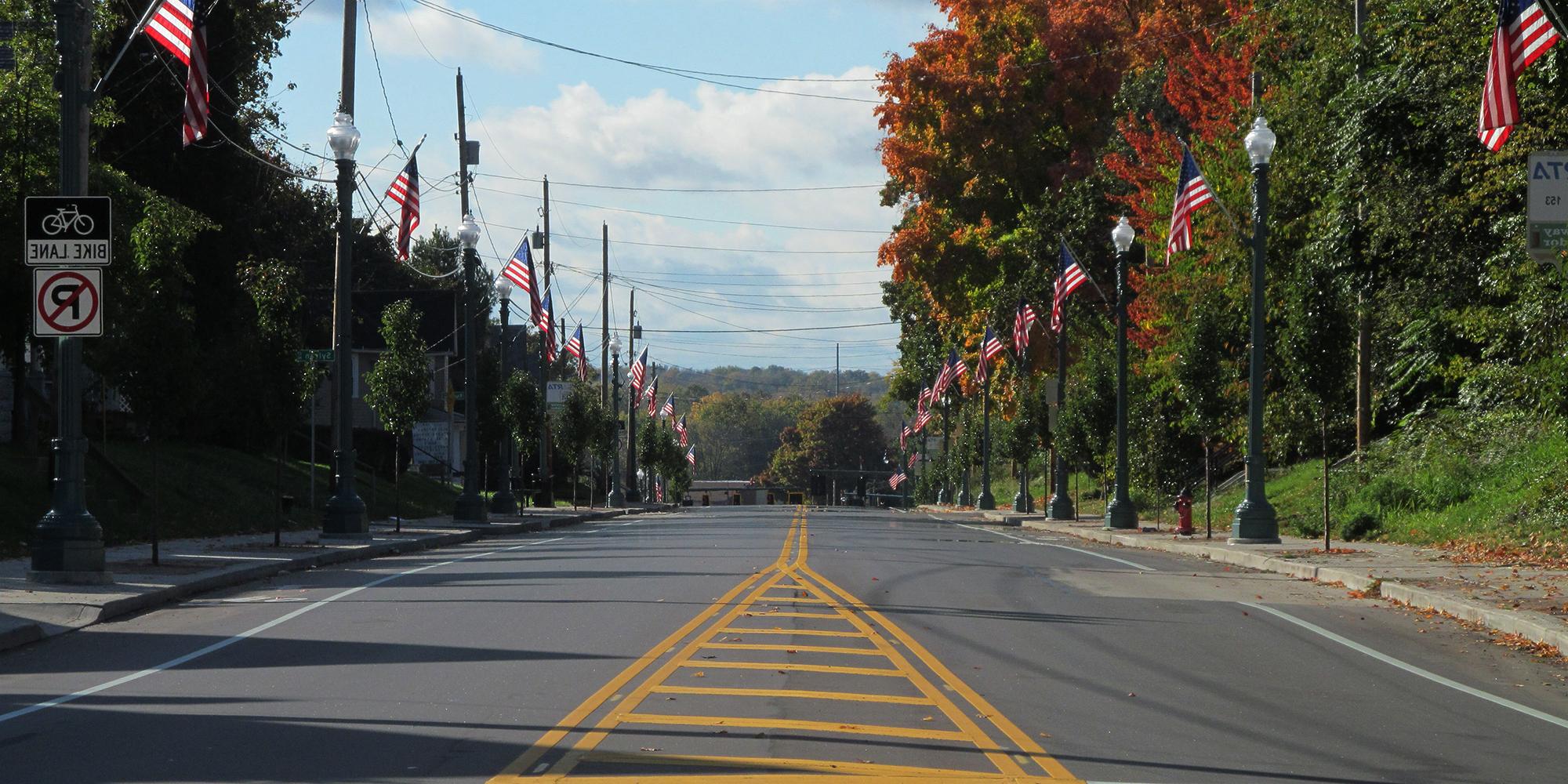 american flags on either side of the road with no cars